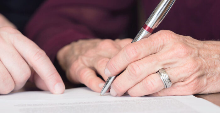 elderly person signing probate document