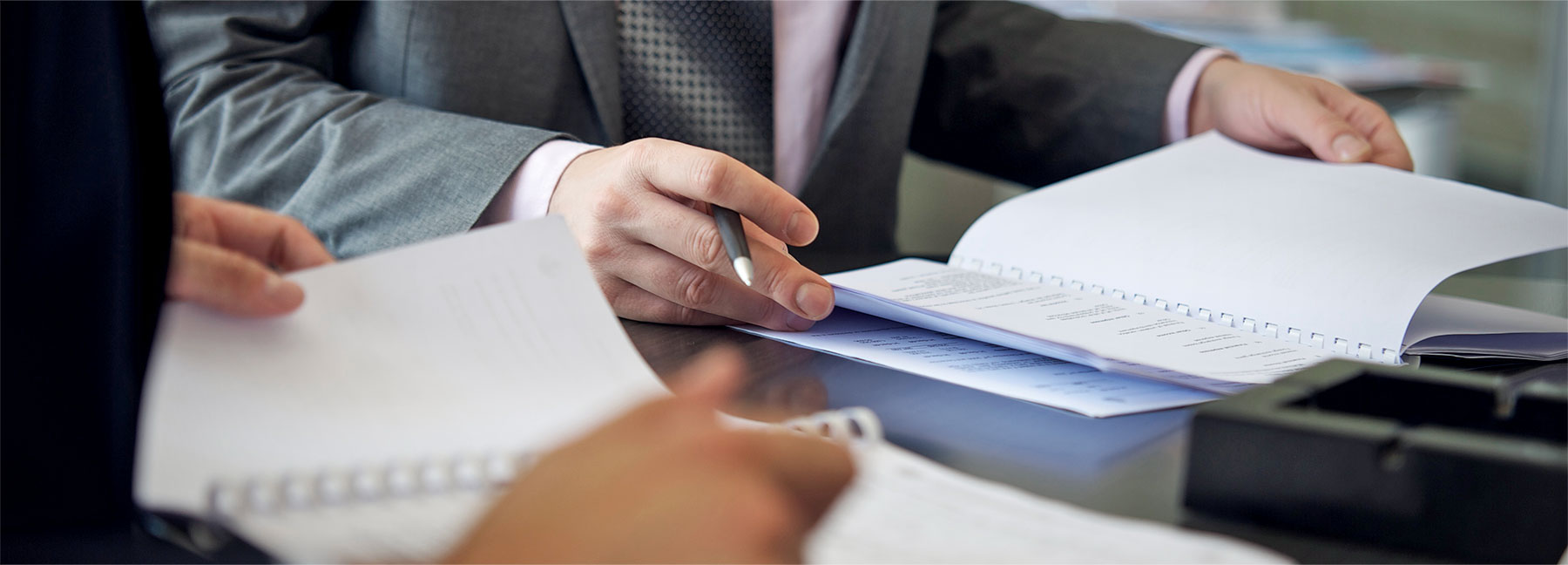 man in suit looking through stack of papers with colleague