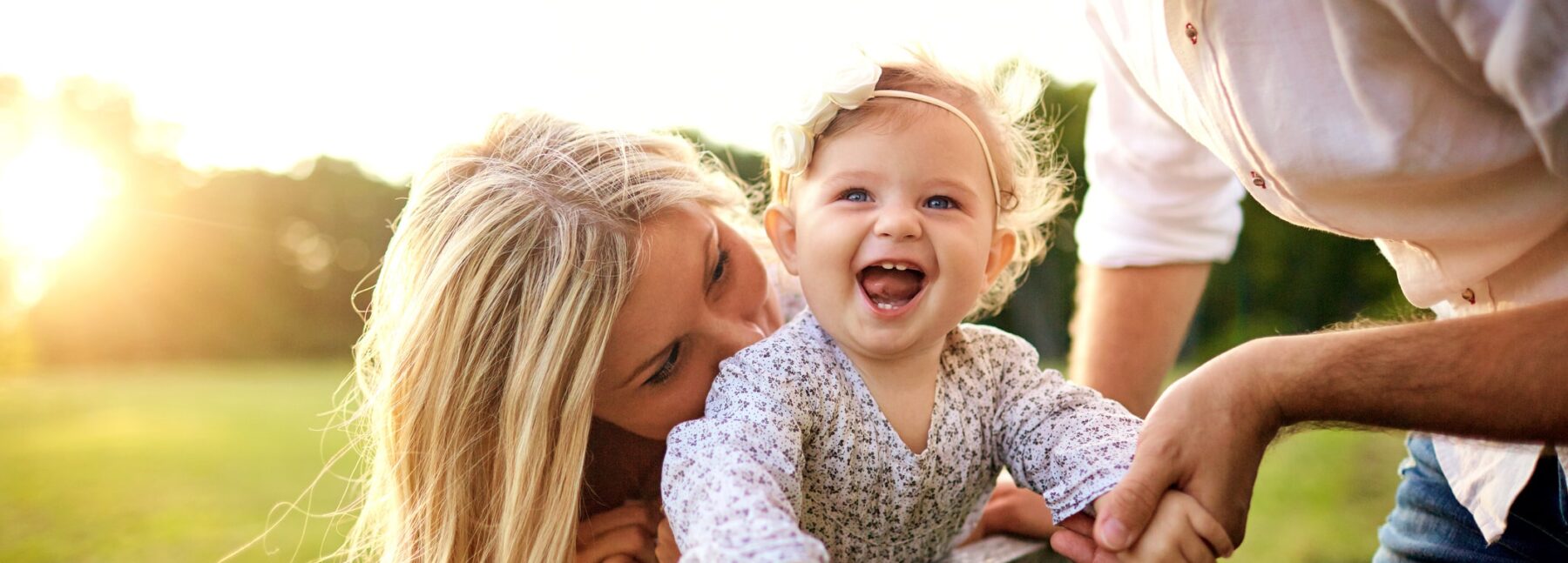 baby girl laughing with parents in the park