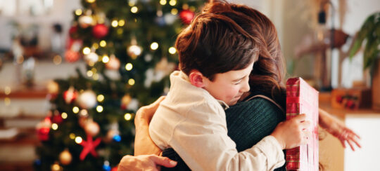 mother and son hugging at christmas in front of the christmas tree