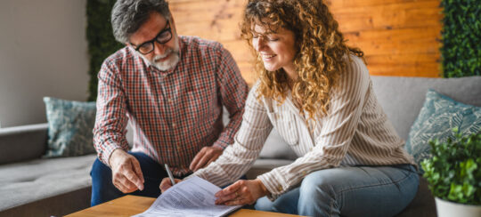 senior man instructs adult woman to sign contract